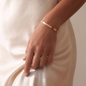 Model wearing a personalised gold bangle bracelet with space for engraving text or coordinates