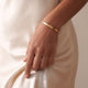 Model wearing a personalised gold bangle bracelet with space for engraving text or coordinates