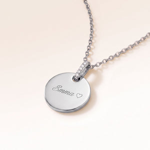 Round silver necklace with zirconia seen from the side with an engraved name and heart
