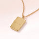 Close-up of a rectangular gold pendant with a soft melted look and personal engraving of initials with a heart on the polished back